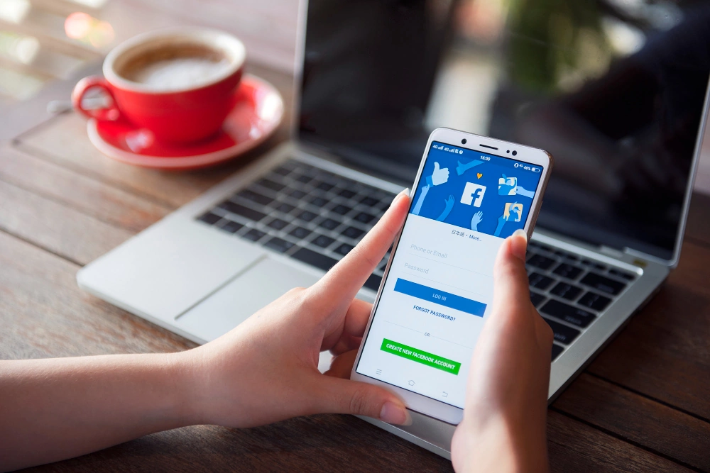 facebook-mainonta-puhelimella Facebook puhelimen näytöllä tietokoneen vieressä